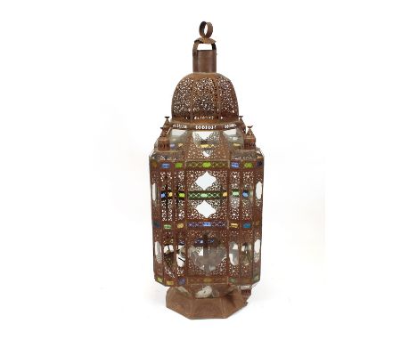 A Middle Eastern metalware and glass floor standing lantern, of large proportions, with pierced decoration and coloured glass