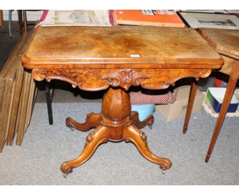 A Victorian walnut card table,  the rectangular fold-over top above a shaped carved frieze and raised on a baluster octagonal
