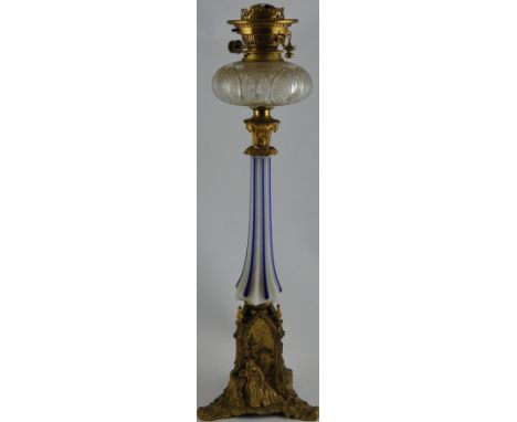 A late Victorian gilt spelter oil lamp with opaque white and blue glass column on architectural triangular cast figural base,