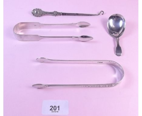Two pairs of silver sugar tongs, a silver button hook and a caddy spoon