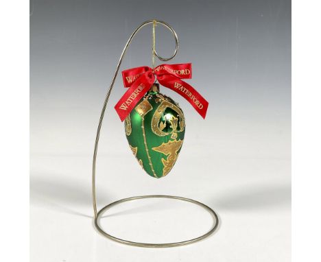 Handcrafted ornament adorned with gold decorative elements that include holly leaves and a stylized fleur de lis crown. The s
