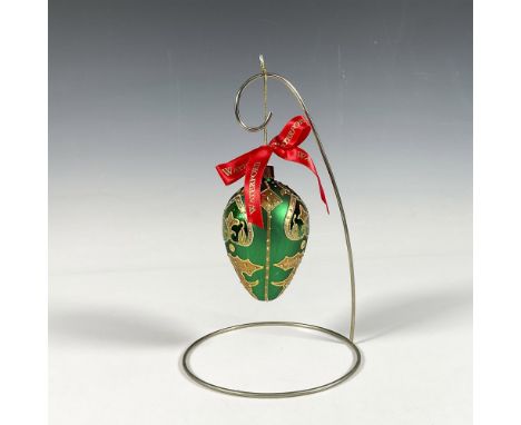 Handcrafted ornament adorned with gold decorative elements that include holly leaves and a stylized fleur de lis crown. The s