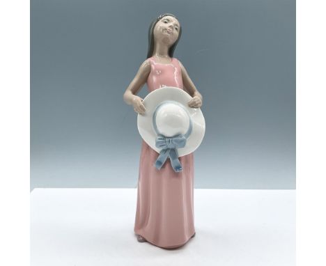 Glossy figural is part of Lladro's historical collection, depicting a young girl, holding her hat and gazing up. Colored in g