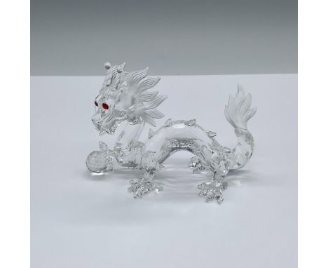 A clear crystal mythical creature with frosted crystal tail and around its head. The Dragon is shown with vibrant red eyes, a