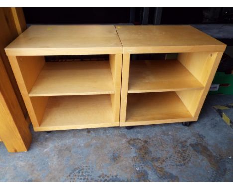 A small pair of open fronted wooden cabinets on castors each with one central shelf 22.5cm (h) x 52cm (w) x 40cm (d)