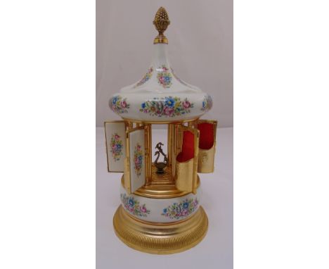 A ceramic and gilded metal cigarette dispenser in the form of a carousel with musical movement, 36cm (h)