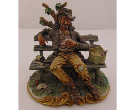 Capodimonte figurine of a gentleman of the road seated on a bench, signed to base, 23cm (h)