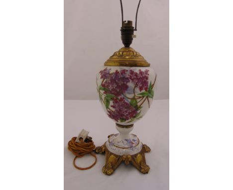 A French ceramic lamp base the ovoid body decorated with flowers and leaves on four gilded metal scroll supports, 37cm (h)