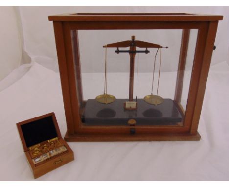 A set of brass balance scales in glazed wooden case to include a cased set of weights, 40 x 45.5 x 23.5cm