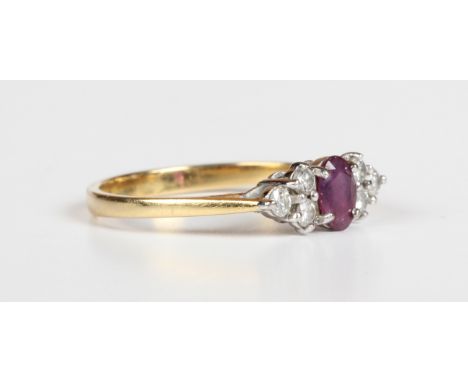 An 18ct gold, ruby and diamond ring, claw set with the oval cut ruby between circular cut diamond set three stone shoulders, 