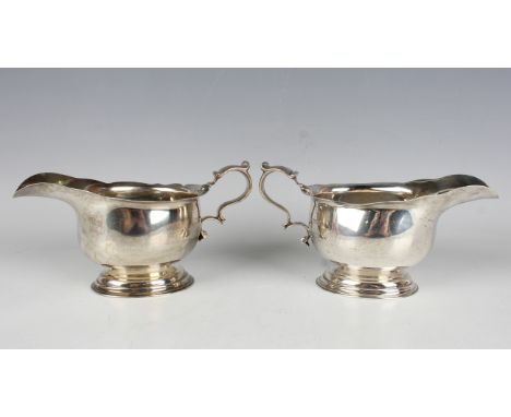 A pair of George V silver sauceboats, each with shaped rim and scroll handle, on a stepped oval pedestal foot, London 1920 by