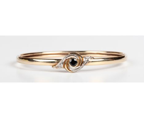A 9ct gold, sapphire and diamond oval bangle, the front collet set with the circular cut sapphire between two diamonds in a t