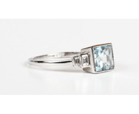 A platinum, aquamarine and diamond ring, collet set with a square cut aquamarine between baguette cut diamond set stepped sho