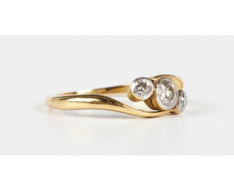 A gold and diamond three stone ring, mounted with a row of cushion cut diamonds in a crossover design, indistinct mark '18ct'