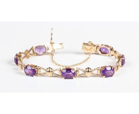 A 9ct gold and amethyst bracelet, claw set with a row of seven oval cut amethysts, on a snap clasp, fitted with a safety chai