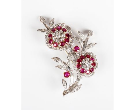 A ruby and diamond brooch, designed as a floral spray with two flowerhead motifs, mounted with circular and baguette cut diam