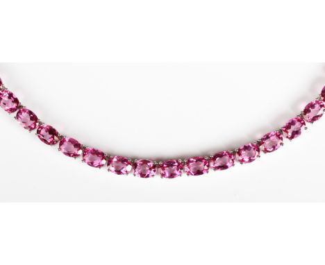 A silver and treated pink topaz necklace, claw set with a row of oval cut treated pink topazes, the sprung hook shaped clasp 