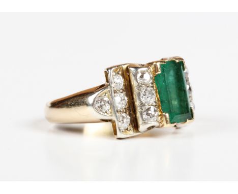 A gold, emerald and diamond ring, 1950s/60s, mounted with the rectangular step cut emerald between diamond set stepped should