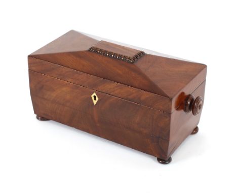 A 19th Century mahogany sarcophagus shaped three compartment tea caddy, flanked by turned handles and raised on bun feet, fit