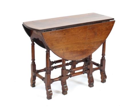 An Antique mahogany gate leg dining table, having rounded drop leaves above two single end drawers, raised on turned columns 