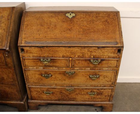An 18th Century oak bureau, the fall front opening to reveal a stepped interior arrangement of drawers and pigeon-holes aroun