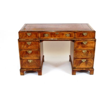 A good quality reproduction walnut pedestal writing desk, having leather top above three frieze drawers with three short draw