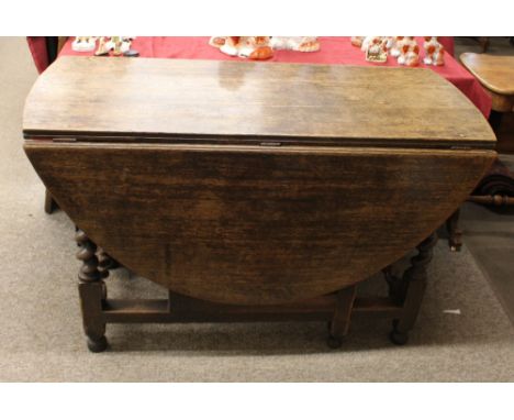 An Antique oak gate leg dining table, having thick rounded drop leaves, raised on spiral turned supports, united by square st