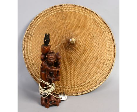 A carved hardwood lamp base fashioned as a Nomad together with a woven coolie hat