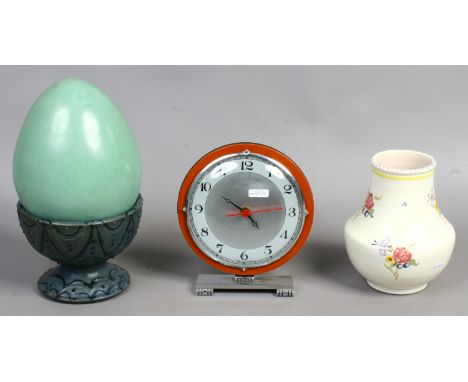 A large art pottery egg on pedestal cup stand, a Poole pottery vase and an Art Deco mantel clock with later quartz movement.