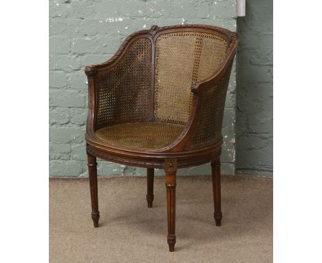 A carved walnut double bergere seat arm chair raised on turned and reeded legs.