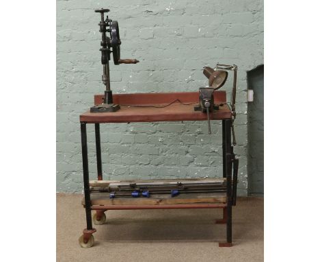 A portable work bench with vice and vintage hand operated cast iron drill, sash cramps, spirit level, angle poise lamp etc