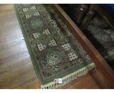 A WOOL RUG the light green and beige ground with central flower filled panel within a conforming border 290cm x 200cm