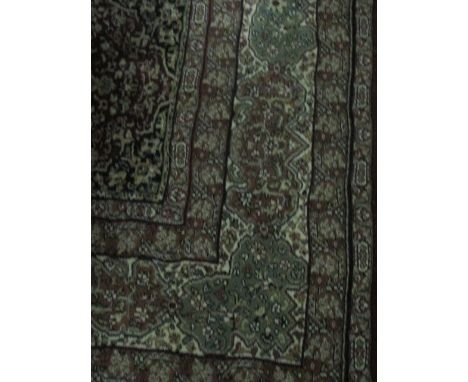 A WOOL RUG the light green and wine ground with overall floral pattern within a conforming border 288cm x 200cm