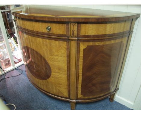A FINE WALNUT AND SATINWOOD COMMODE of demi-lune outline the shaped moulded top above a frieze drawer and cupboard with oval 