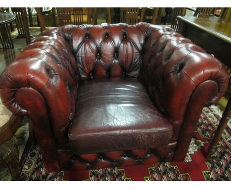 A WINE HIDE UPHOLSTERED LIBRARY CHAIR with deep button upholstered back and seat with roll over arms and loose cushion on cas