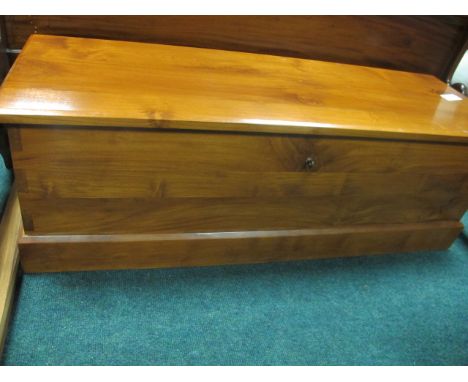 A CHERRYWOOD TRUNK the rectangular hinged lid containing a slide tray with carrying handles on platform base 46cm (h) x 137cm
