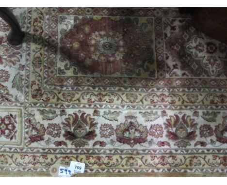 A WOOL RUG the beige light brown and green ground with panels filled with palmets within a floral border 236cm x 153cm
