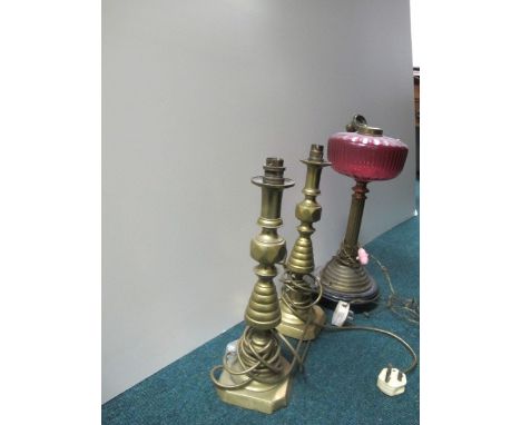 A VICTORIAN BRASS AND RUBY GLASS PART OIL LAMP together with a pair of brass table lamps 48cm high