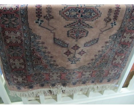 A PAKISTAN WOOL RUG the light pink and beige ground with central panel with palmets and stylized flowerheads within a four st