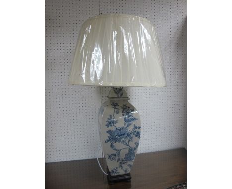 A PORCELAIN TABLE LAMP the white and blue ground decorated with flowerheads and foliage raised on a hardwood base with pleate