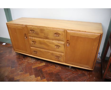 Modern Ercol Sideboard with three central drawers and two side cupboards in light wood. H:27 x W:61 x D:17 inches. In very go
