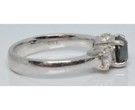 An 18ct white gold ring set with a round cut black diamond flanked by two diamonds, each approximately 0.25ct, 5.94g, size M