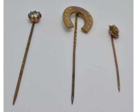 A 9ct gold stick pin set with a diamond, a Victorian yellow metal stick pin in the form of a horse shoe and a paste stick pin