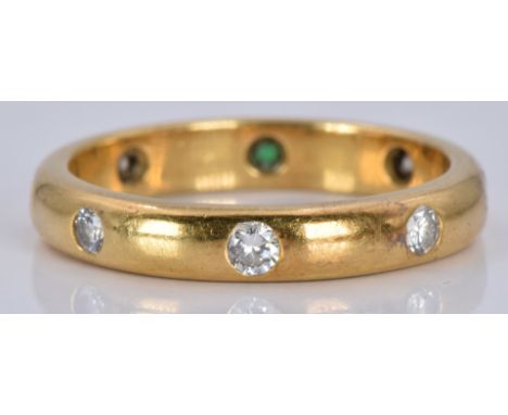 An 18ct gold eternity ring set with an emerald and diamonds, 4.4g, size M