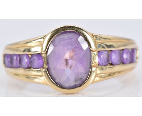 A 9ct gold ring set with an oval cut amethyst and four further round cut amethysts to each shoulder, 3.1g, size N