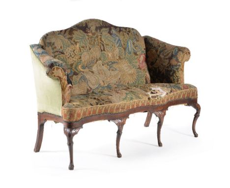 A George II walnut and tapestry upholstered sofa, circa 1735, the arch shaped back above a pair of shaped scroll arms, the pa