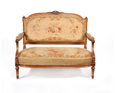 A Victorian solid satinwood, parcel gilt and tapestry upholstered settee, circa 1870, the moulded cresting rail centred by a 