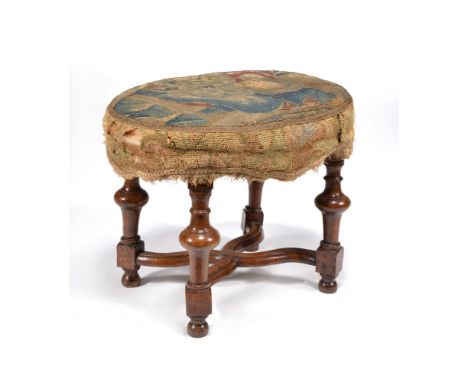 A William III walnut oval stool, circa 1700, the padded and tapestry upholstered seat above turned and square section legs jo