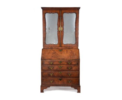 A George II walnut and feather banded bureau bookcase, circa 1740, in the manner of Giles Grendy, the stylised Vitruvian scro