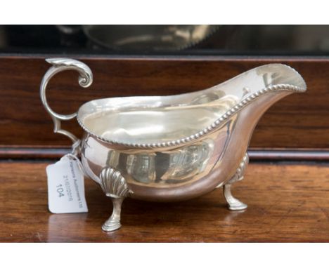 A George V silver sauce boat, Sheffield 1926, with a gadrooned border and raised on three hoof feet in the George II style ma